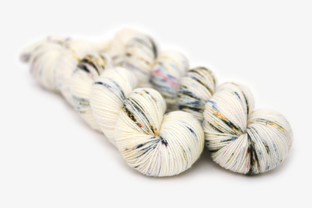 speckled hand dyed white olive yellow blue merino sock yarn
