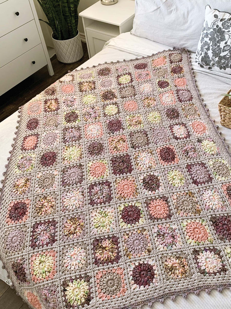 Opalescent color palette blanket in crochet laid out on bed