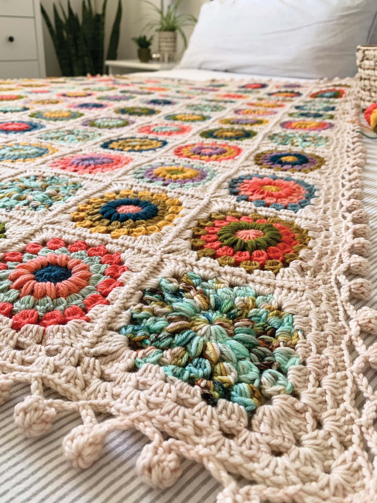 blanket on a bed, made out of semisolid speckled hand dyed desert colors of dk yarn